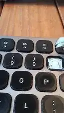 The key cap should be lifted from the top edge. You can use any "tool" that allows you to get under the top edge, and lift the edge away. Something flat and relatively thin will do (like a small flat-head screw driver). In this video I am using some tweezers.