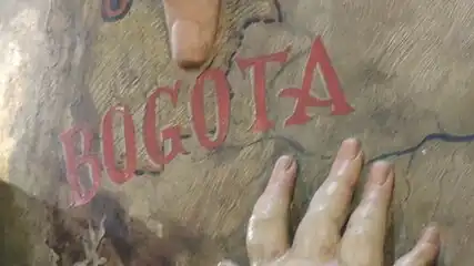 Dedos de los ángeles señalando la ubicación de Bogotá en la esfera terrestre