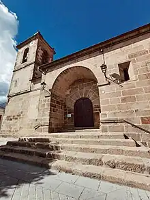Fachada principal de la Iglesia de San Pedro Advincula, en Pedro Bernardo. La fotografía está tomada desde una perspectiva algo contrapicada. Unas escaleras de piedra llevan a la entrada principal del templo, que tiene una única torre en la parte izquierda