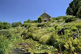 Vista de la capilla Sainte-Valérie, alpinum y charca de plantas acuáticas.