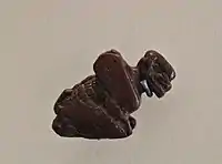 Talla de jaspe rojo de un Pazuzu en cuclillas, esta postura agachada sugiere su conexión con el Viento del Oeste. Museo del Louvre.