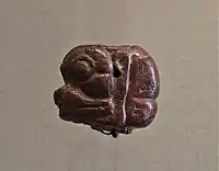 Cabeza de Pazuzu en piedra roja con inscripción. Museo del Louvre.
