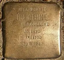 Primer plano del Stolpersteine o piedra de tropiezo hecha en lo que parece bronce y en la que se puede leer: «Hier wohnte Ida Dehmel Geb. Coblenz. JG. 1870 Freitod. 29/9/1942