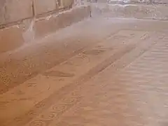 Detalle del mosaico geométrico de cubos con la tira perimetral de volutas de hiedra y máscaras de teatro.