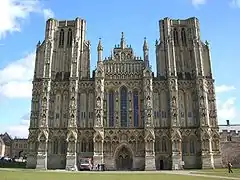 La catedral de Wells tiene torres, una galería esculpida y una ventana de lanceta. La fachada de Wells, a diferencia de la de Exeter, presenta una composición unificada y equilibrada. Sin embargo, las torres aparecen truncadas porque se pretendía que tuvieran agujas, que no fueron construidas
